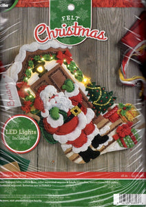 Bucilla felt stocking kit. Design features santa  with his pack of toys on a decorated front porch. This stocking kit lights up.