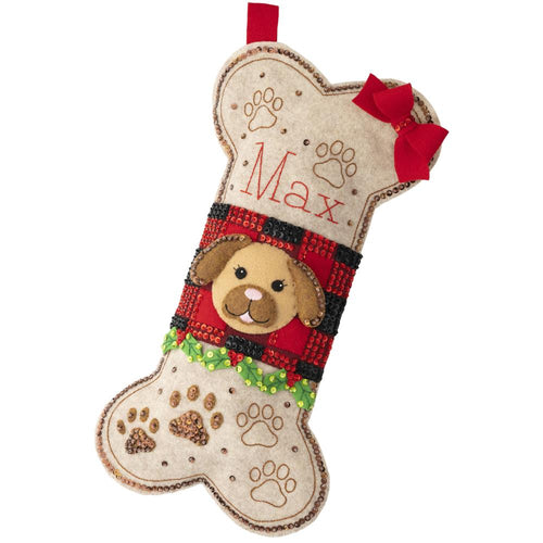 Bucilla felt christmas stocking kit. Design features a dog face in the middle of a bone shaped stocking. Paw prints in the background.