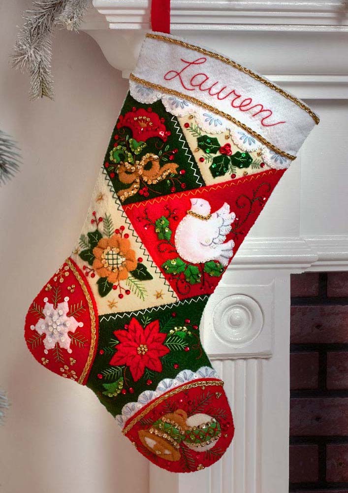 Bucilla felt christmas stocking kit. Design features a red, green, and cream patchwork pattern with bells, a dove, and poinsettia.