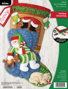 Bucilla felt stocking kit. Design features a  living room scene with a sleeping snowman holding a teddy bear. A cat lays nearby and santa in on his way down the chimney.
