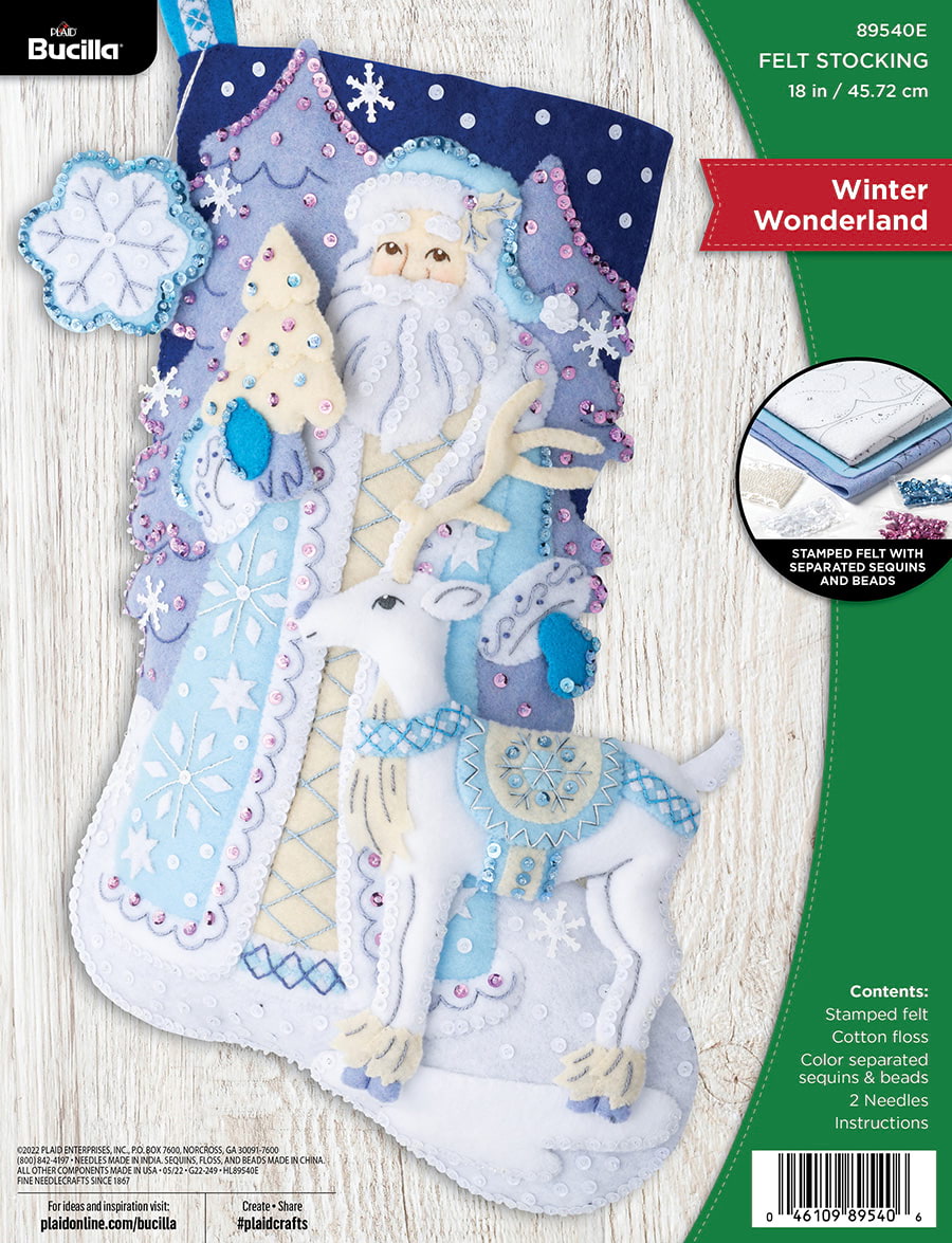 ucilla felt christmas stocking kit. Design features a santa dressed in light blue and cream next to a white deer. The background features light purple trees. Blues and Purples are predominant in this stocking. 